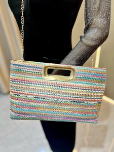 Detail showing the colorful woven straw texture and gold chain strap of the handbag