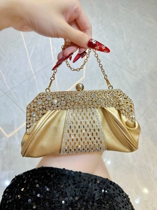 Détail d'une pochette de soirée dorée avec strass scintillants et chaîne en métal