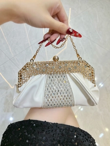 Détail des strass en cristal et du cadre en métal doré sur un sac de soirée blanc