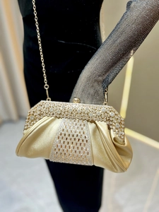 Détail de la pochette de soirée dorée avec plis élégants et strass étincelants