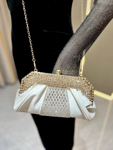 Détail d'une pochette de soirée blanche ornée de strass brillants et d'une chaîne dorée