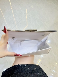 Detailed interior of silver satin evening clutch showing metal chain and rhinestone clasp