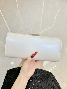 Close-up of white clutch bag with textured finish and elegant silver rhinestone buckle