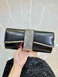 Detail of elegant black evening clutch featuring rhinestone band and silver metal trim