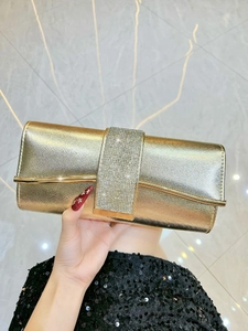 Detailed view of luxury gold clutch with rhinestone buckle and crosshatch texture