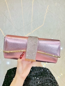 Detail of metallic pink evening clutch with a wide sparkling rhinestone band and gold trim