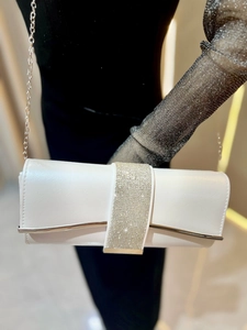 Close-up of a white textured evening clutch with sparkling rhinestones and silver chain