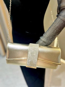 Detail of gold evening clutch bag featuring rhinestone strap and metallic chain