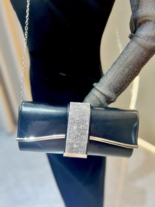 Close-up of black dinner clutch with rhinestones and silver arc accent on fabric