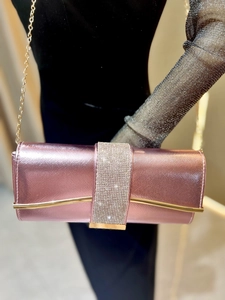 Detail of rose gold evening clutch bag with sparkling rhinestones and golden chain strap