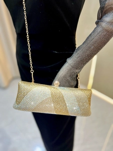 Détail d'une pochette de soirée luxueuse avec strass dorés et chaîne en métal
