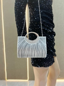 Detail der silbernen Strass-Clutch mit rundem Metallgriff und funkelnder Streifentextur