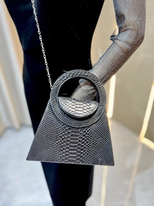 Detail view of silver snake-embossed triangular handbag with metal chain strap
