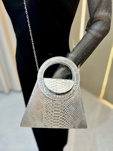 Macro shot of silver snakeskin texture and circular handle on a metallic shoulder bag