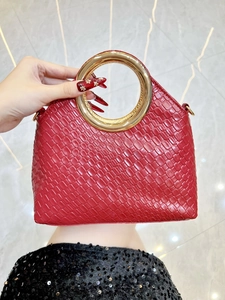 Close-up of red woven evening handbag with gold circular metal handle detail