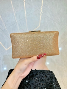 Macro view of golden glitter texture and metallic clasp on a rectangular evening clutch