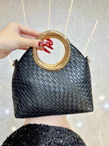 Macro shot of black woven texture bag with a luxury oversized gold circular metal handle