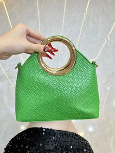 Detail of green faux leather handbag with woven pattern and large gold circular handle