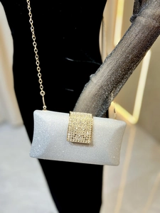Detail of silver glitter evening bag with rhinestone buckle and gold chain strap