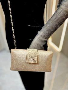 Detail of champagne gold sequin clutch bag with crystal buckle and gold chain strap