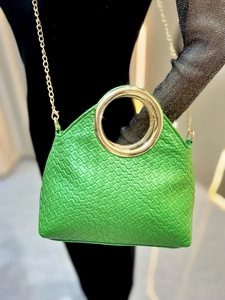 Detail of green woven handbag with round gold metal handle and slim chain strap