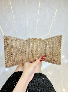 Detail of evening clutch bag featuring a bow shape and champagne sparkling rhinestones