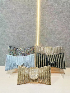 Sparkling rhinestone bow clutch evening bags in various colors on a display stand