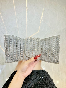 Detailed close-up of a silver evening clutch bag with sparkling crystals and bow design