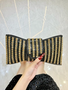 Detail of a luxury bow-shaped evening clutch bag with black rhinestones and golden crystals