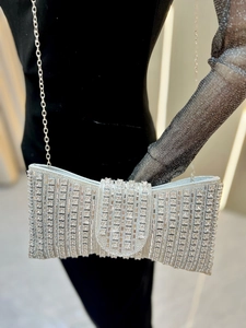 Macro shot of silver rhinestone evening clutch with shimmering bow-knot design and chain
