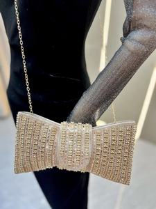 Detail of luxury champagne gold bow evening clutch with sparkling rhinestones and chain strap