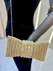 Close-up of luxury gold evening clutch bag with sparkling rhinestones and metal chain