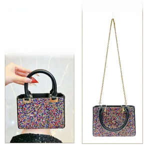 Detail of colorful rhinestone evening bag showing dual metal chain and handheld strap