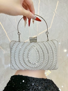 Detailed macro of vintage evening clutch with white pearls, rhinestones and metal ring handle