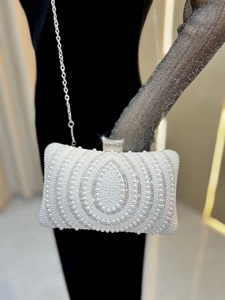 Detailed macro of white pearl evening bag with sparkling rhinestone patterns and silver clasp
