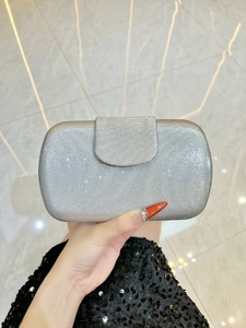 Détail d'une pochette de soirée argentée à rayures pailletées et fermoir aimanté