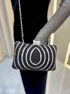 Close-up of luxury evening clutch bag featuring intricate silver rhinestones and metal chain