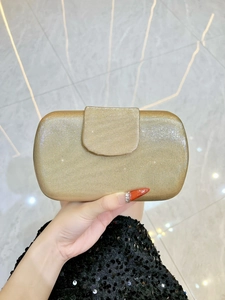 Détail d'une pochette de soirée dorée avec texture à rayures verticales et fini scintillant