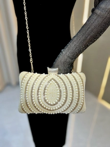 Detail of evening clutch with ivory pearls in drop patterns and rhinestone metal clasp