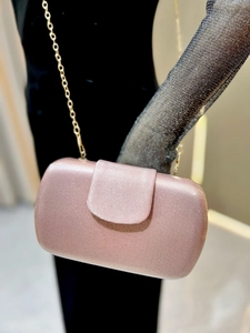 Détail d'une pochette de soirée or rose avec rayures verticales et chaîne dorée