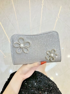 Detail view of silver sequin evening bag featuring 3D rhinestone flowers and pearl accents
