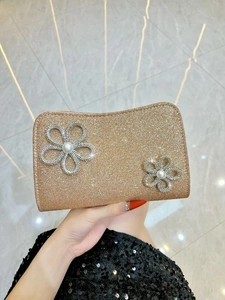 Detail of gold sequin evening clutch featuring crystal floral accents and a center pearl