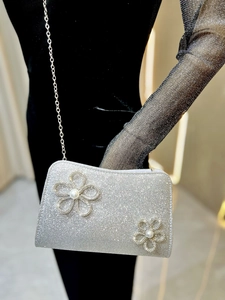 Close-up of silver glitter evening bag with pearl flower accents and metal chain strap