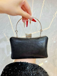 Detail of black evening clutch with silver metal ring handle and rhinestone clasp