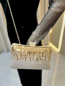 Close-up of luxury gold clutch bag with sparkling rhinestones and elegant gold chain strap