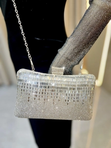 Detailed view of silver rhinestone evening clutch bag with crystal fringe on black velvet