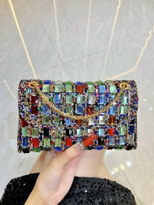 Detailed close-up of a colorful crystal-embellished evening clutch with gold chain strap