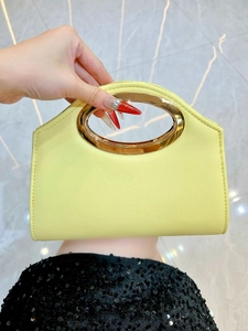 Detail of lemon yellow woven handbag with circular gold metal handle for women