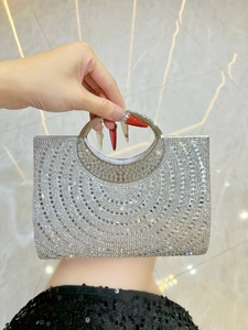 Close-up of silver rhinestone evening bag with circular metal handle and geometric patterns
