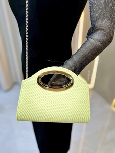 Fashionable woven clutch bag with gold oval metal handle and chain strap in lime yellow